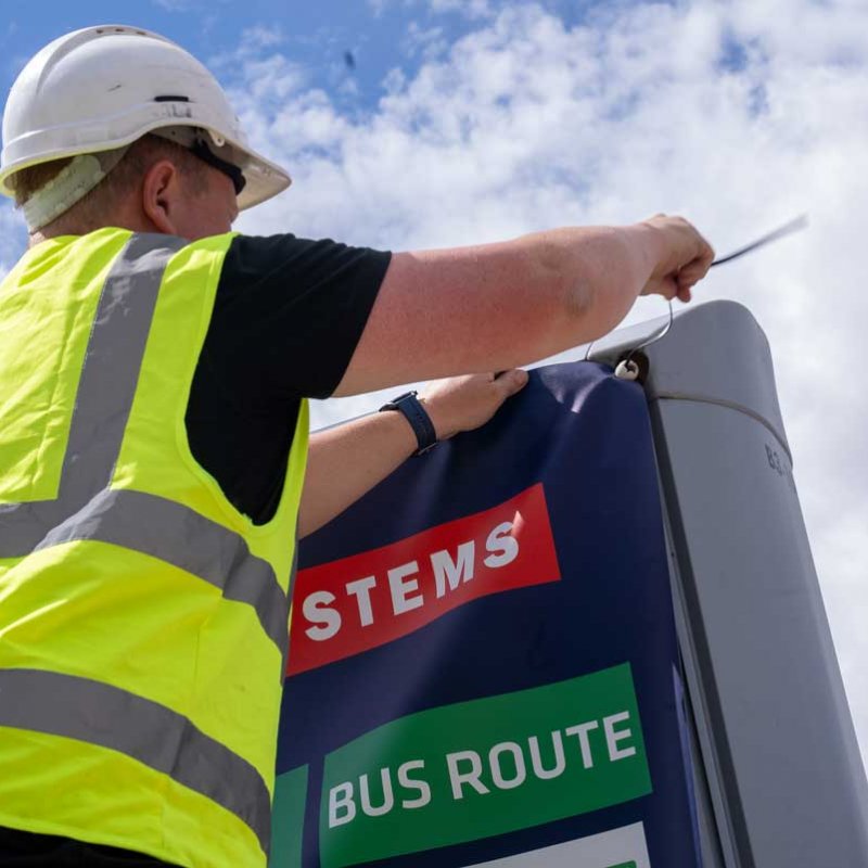 Trotter staff member replacing graphics on an outdoor billboard