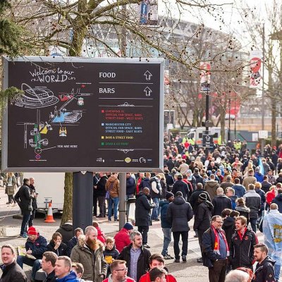 welcome to our world temporary billboard and event signs, placed by the entrance of wembley stadium. The signage is large format outdoor signage is being used as wayfinding signage for the crowds. It has the words food and bars with arrows and a map to direct them